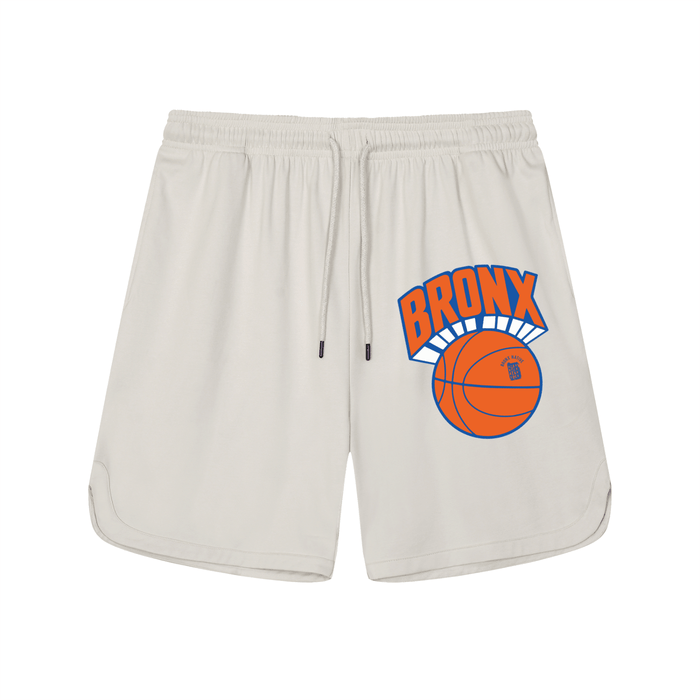 Cream Bronx basketball shorts with bold orange 'BRONX' graphic and ball design, NYC streetwear style